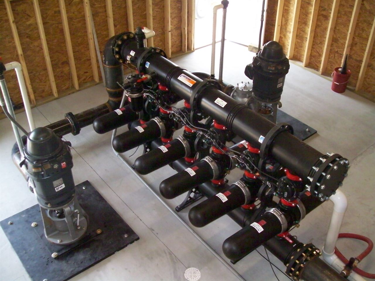 A bank of automatic self-cleaning disc filters with backflush manifold and booster pump installed in a pump house